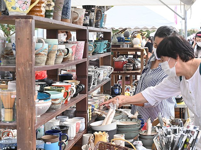 マグカップを品定めする買い物客＝多治見市旭ケ丘、多治見美濃焼卸センター