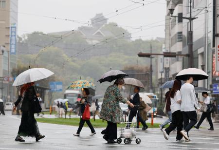 　雨が降る中、傘を差して熊本市内を歩く人たち。奥は熊本城＝２６日午前