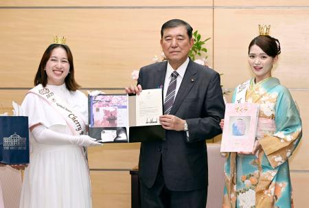 　全米さくらの女王のマリサ・ボワカムさん（左）からトランプ米大統領の親書を受け取る石破首相（中央）＝１２日午後、首相官邸
