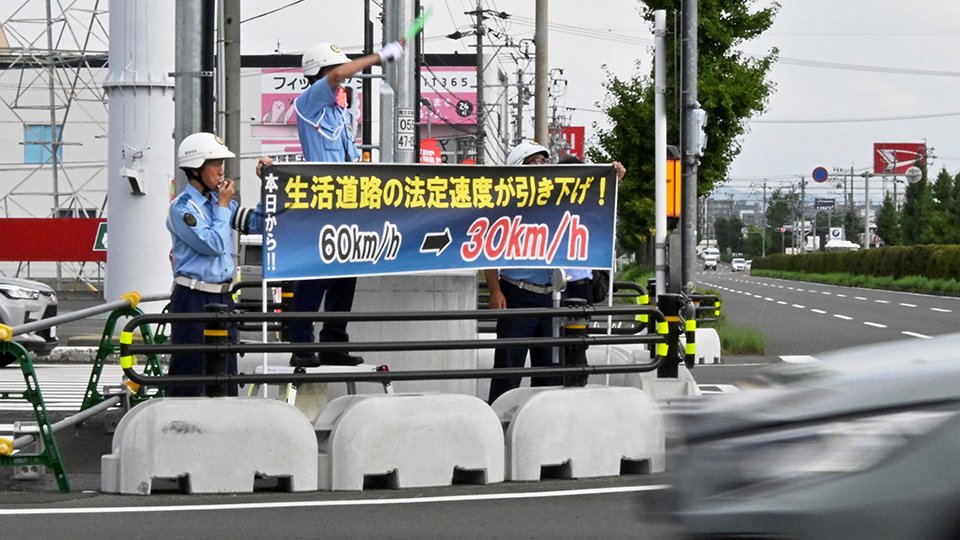横断幕を掲げ法定速度引き下げを知らせる署員ら＝岐阜市茜部菱野、茜部中島交差点