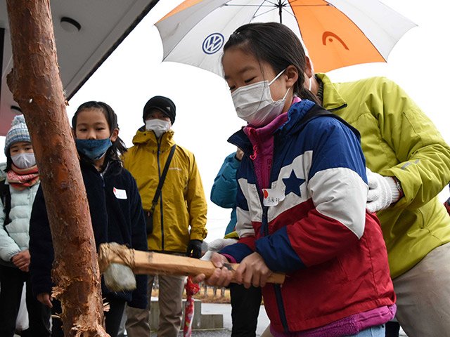 石斧で木を切る子ども＝高山市赤保木町、市風土記の丘学習センター
