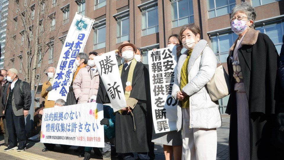 「勝訴」と書かれた垂れ幕などを掲げる原告ら＝２１日午後、岐阜地裁前