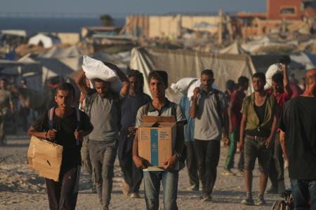 　パレスチナ自治区ガザ北部ガザ市で世界食糧計画（ＷＦＰ）の食料を運ぶパレスチナ人＝２４日（ＡＰ＝共同）