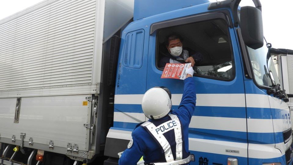 大型車のドライバーにチラシとホイールナットマーカーを配布する県警高速隊員＝養老郡養老町橋爪、名神高速道路下り線養老サービスエリア