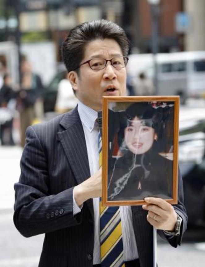 　有本恵子さんの写真を手に署名活動する拉致被害者家族会代表の横田拓也さん＝２６日午前、東京・銀座