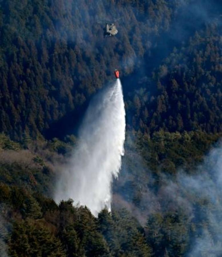 　延焼が続く山梨県上野原市の扇山で、消火活動を行う陸上自衛隊のヘリコプター＝１２日午前１０時５分（共同通信社ヘリから）