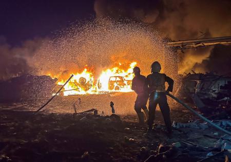 　ガザ南部ハンユニスで、イスラエル軍の空爆を受け消火に当たる人＝２８日（ロイター＝共同）