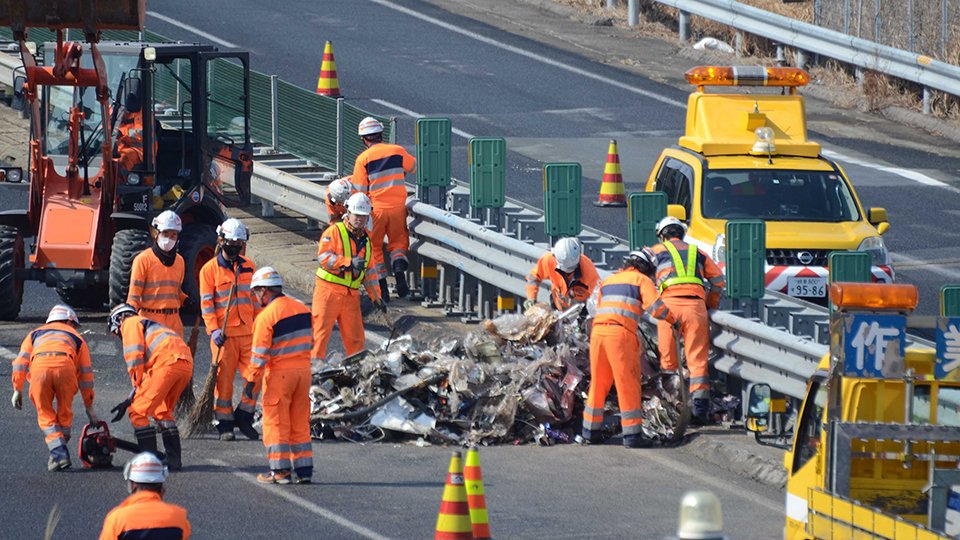 中央自動車道下り線の道路上に散乱した鉄くずなどを撤去する作業員＝２日午前１０時５７分、中津川市千旦林