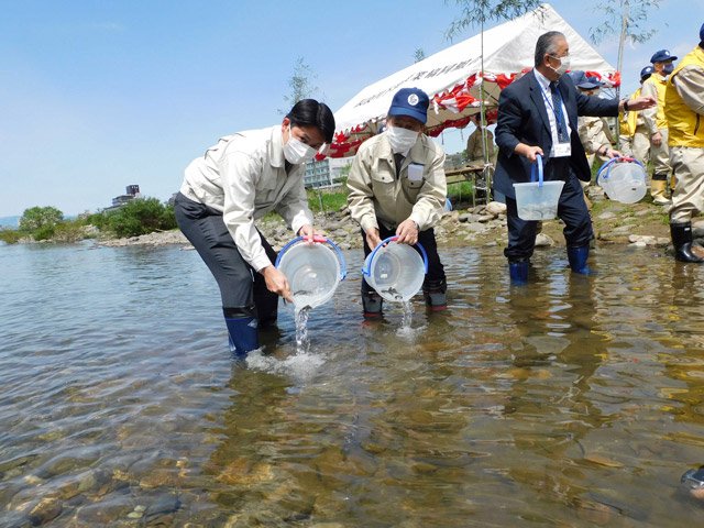 稚鮎を放流する柴橋正直市長と玉田和浩組合長（左から）＝２０２１年４月、岐阜市長良、長良川右岸