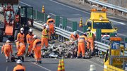 中央自動車道下り線の道路上に散乱した鉄くずなどを撤去する作業員＝２日午前１０時５７分、中津川市千旦林