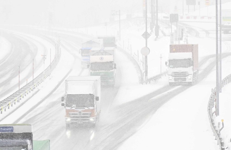 寒波に伴う雪の中を走るトラック＝２４日午後０時１７分、郡上市高鷲町、東海北陸道