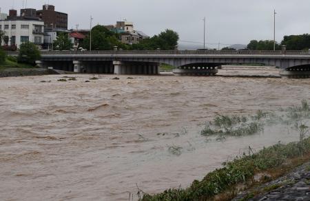 　大雨で増水し、激しく流れる鴨川。奥は賀茂大橋＝２６日午前９時４分、京都市左京区