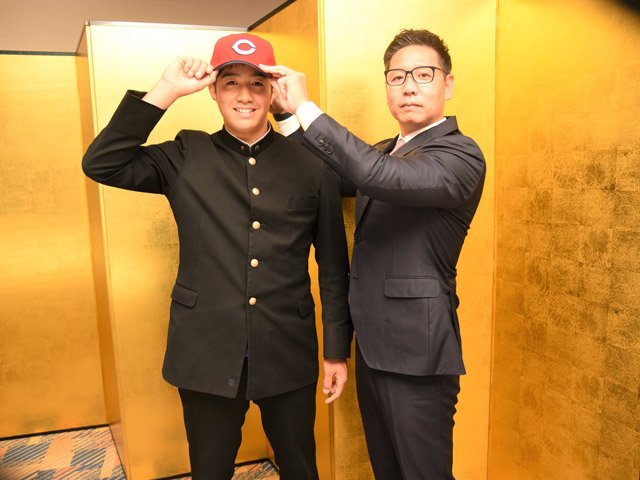 松本有史スカウト（右）に帽子をかぶせてもらい、意気込む高木翔斗捕手＝岐阜市内