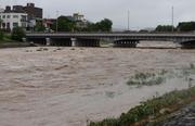 　大雨で増水し、激しく流れる鴨川。奥は賀茂大橋＝２６日午前９時４分、京都市左京区
