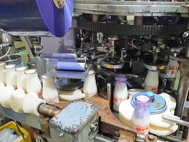 飲み口にビニールひもとフードが取り付けられる牛乳瓶＝関市観音前、関牛乳