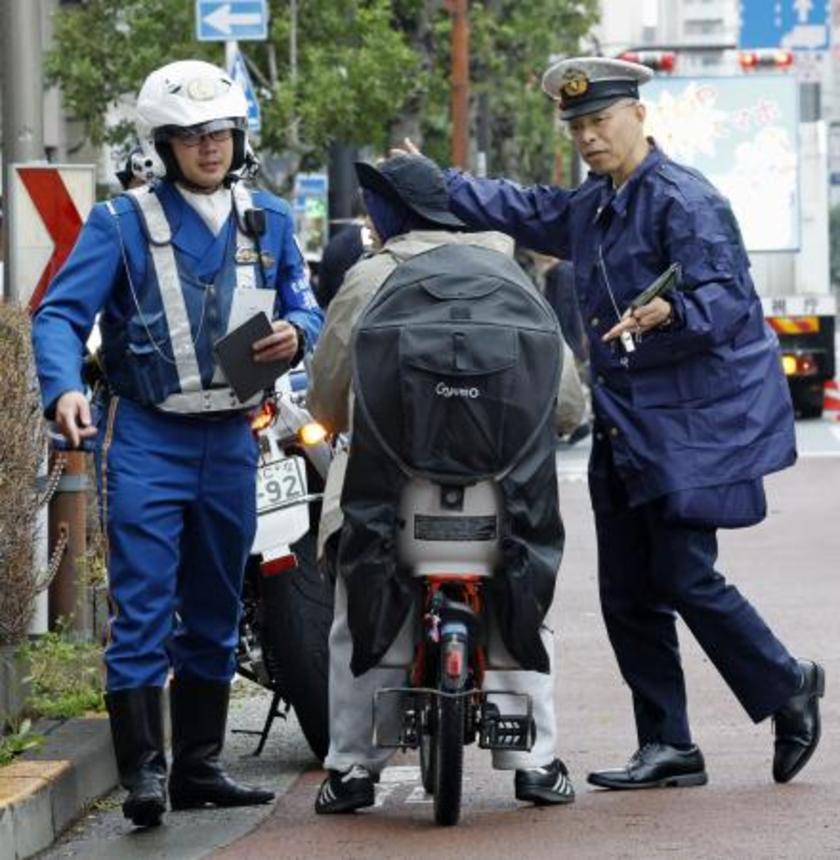 　１６歳以上の自転車の交通違反に反則金納付を通告できる交通反則切符（青切符）制度が始まり、東京都北区の交差点付近で利用者に指導する警察官＝４月１日