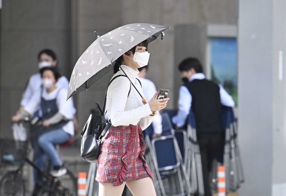 今季最高気温の夏日の中、日傘を差して歩く女性＝２０日午後３時１９分、岐阜市神田町
