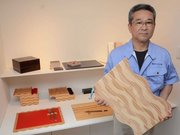波形のデザインが目を引くバスマットを手にする内木盛良社長＝中津川市付知町、内木木工所