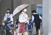 今季最高気温の夏日の中、日傘を差して歩く女性＝２０日午後３時１９分、岐阜市神田町