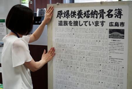 　広島市役所で「原爆供養塔納骨名簿」のポスターを掲示する職員＝１１日午前