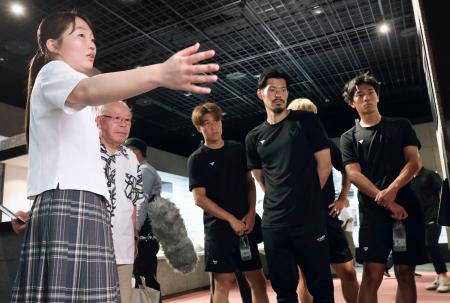 　高校生平和大使（手前）の案内で長崎原爆資料館を見学するサッカーＪ２長崎の選手ら＝９日午後、長崎市