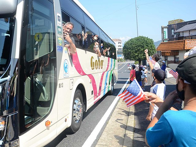 バスで練習会場に向かう米国選手団に声援を送る東小学校の児童ら＝２０日、中津川市花戸町