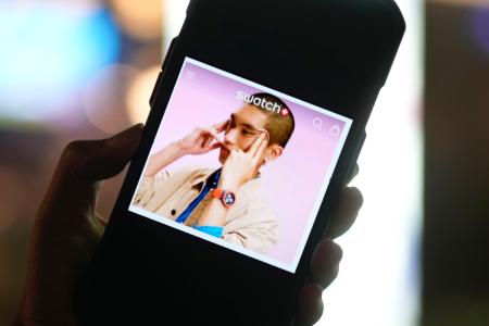 　モデルが「つり目」のポーズをしたスウォッチ・グループの広告を表示するスマートフォンの画面（共同）