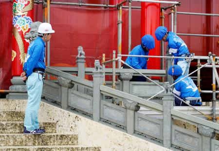 　首里城正殿の正面に高欄を設置する作業員＝１２日午前、那覇市
