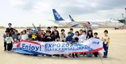 　万博を記念した全日空の特別デザイン機を前に記念撮影する小学生ら＝１９日午後、能登空港