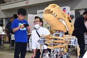 　巡回型展示会「ＫＯＳＥＮ　ＰＡＲＫ」で、小山高専の名物ロボットを操作体験する来場者（左）＝１７日午後、宇都宮市