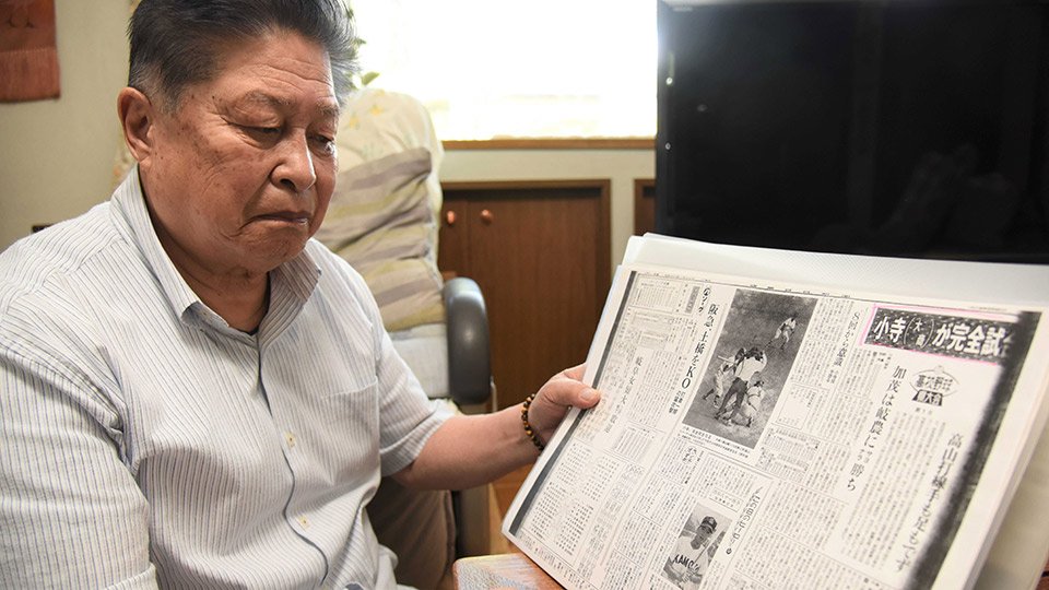 完全試合を達成した翌日の岐阜日日新聞の記事を懐かしそうに眺める小寺進さん＝可児市皐ケ丘