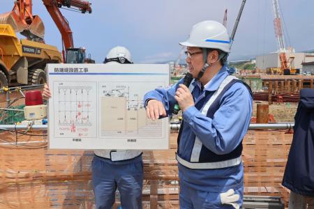 　防潮堤の新設工事中について説明する北海道電力の世戸洋行・土木建築課長＝１日午前、北海道泊村の泊原発敷地内