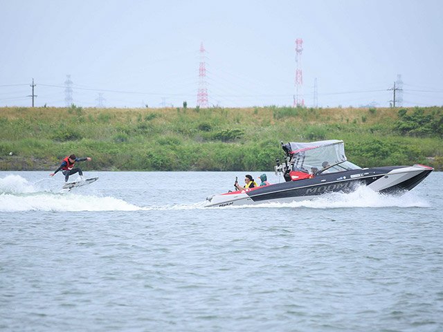 ボートの引き波で華麗な波乗りを見せる出場者＝海津市海津町油島、長良川
