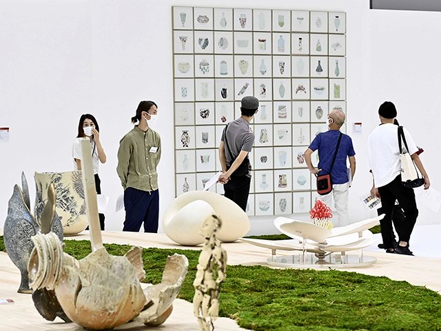 開幕した国際陶磁器展美濃で、グランプリの壁面作品（奥）を鑑賞する来場者。展示台にはコケが植えられている＝多治見市東町、セラミックパークＭＩＮＯ