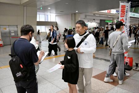 　ＪＲ川崎駅付近で署名活動をする岡崎彩咲陽さんの父鉄也さん（手前右）ら＝６月