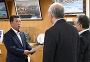 　北海道泊村議会の議長らから意見書を受け取る高橋鉄徳村長（左）＝３１日午前、北海道泊村
