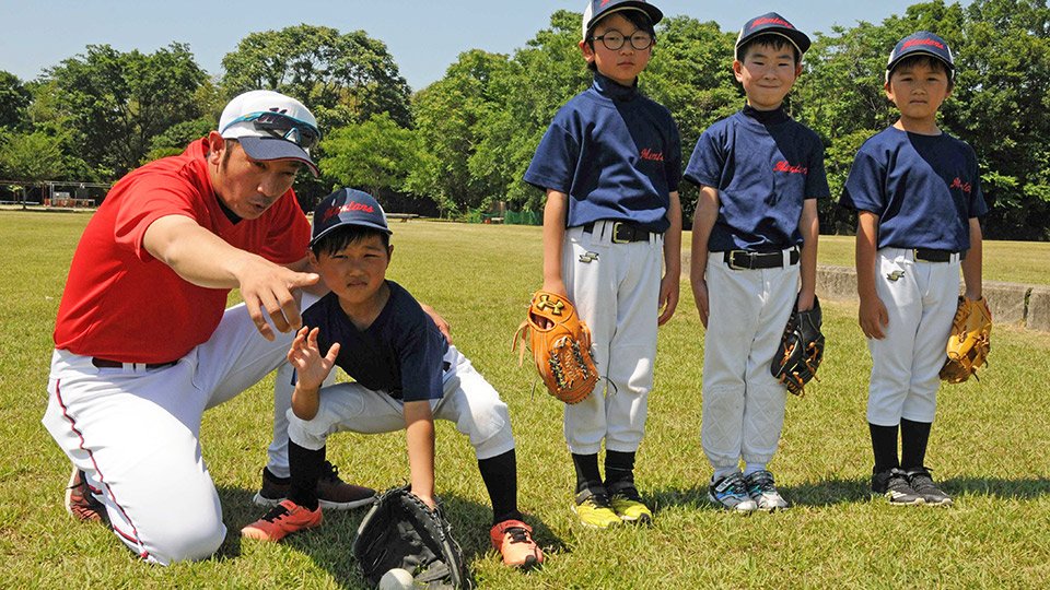小学生にゴロの捕り方を丁寧に教える脇田博之さん（左）＝羽島郡笠松町、米野グラウンド