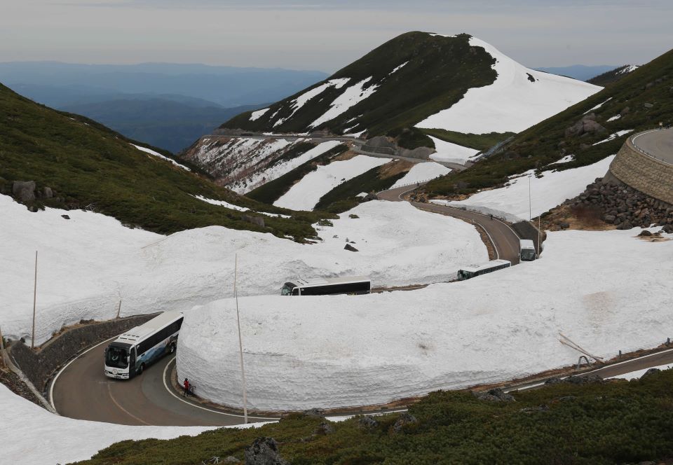 開通した乗鞍スカイラインで、雪の壁の間を縫って進むバス＝高山市丹生川町　