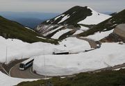 開通した乗鞍スカイラインで、雪の壁の間を縫って進むバス＝高山市丹生川町　