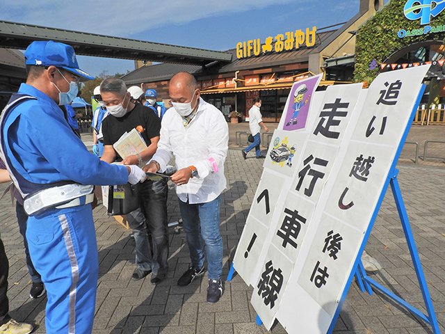 高速道路利用者にチラシを配布する吉田和浩県警高速隊長（左）＝各務原市川島笠田町、川島パーキングエリア