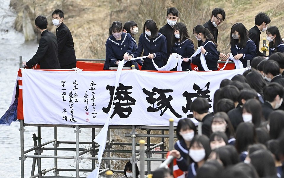 伝統の「白線流し」で結んだスカーフを流す卒業生ら＝１日午後０時４８分、高山市大新町、大八賀川