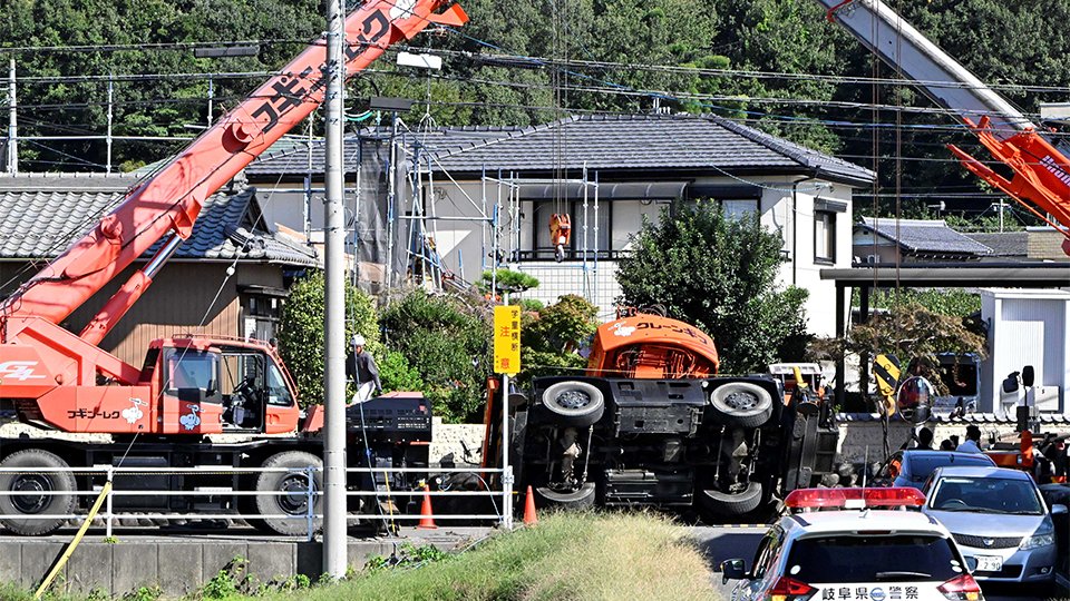 民家に転倒したクレーン車＝２３日午後１時１４分、岐阜市城田寺