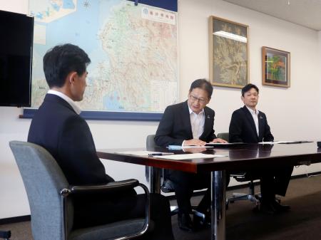 　福井県の坂本裕一郎防災安全部長（左）と面会する関西電力の高畠勇人原子力事業本部長代理（中央）＝１２日午後、福井県庁