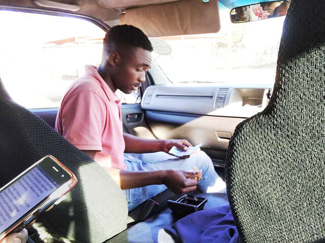 乗り合いタクシーの助手席で運賃を計算する乗客＝南アフリカ共和国