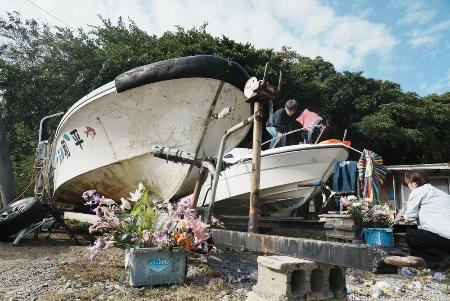 　辺野古沖で転覆した船「平和丸」（左）と「不屈」に花を供える人たち＝３月、沖縄県名護市