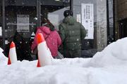 　雪が積もる中、福井県知事選の投票所に向かう人たち＝２５日午後、福井市