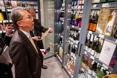 　ウクライナ・キーウのスーパーに陳列された日本酒を見る日本の代表団のメンバー＝２８日（共同）