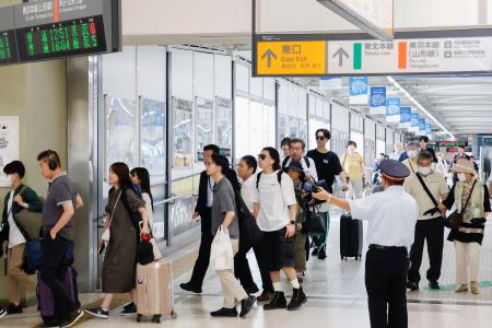 　駅員に誘導され、山形新幹線から東北新幹線に乗り換える乗客ら＝１９日午前、ＪＲ福島駅