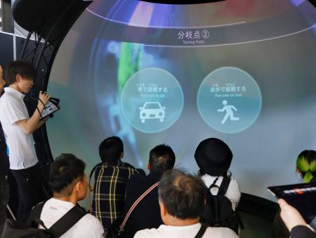 　災害発生時の避難行動を体験できる映像を見る来場者＝５月、大阪市此花区の夢洲