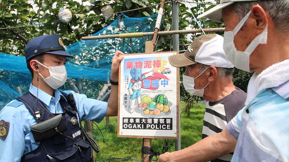 「果物泥棒警戒中」と書かれたポスターを掲示する大垣署員ら＝大垣市曽根町